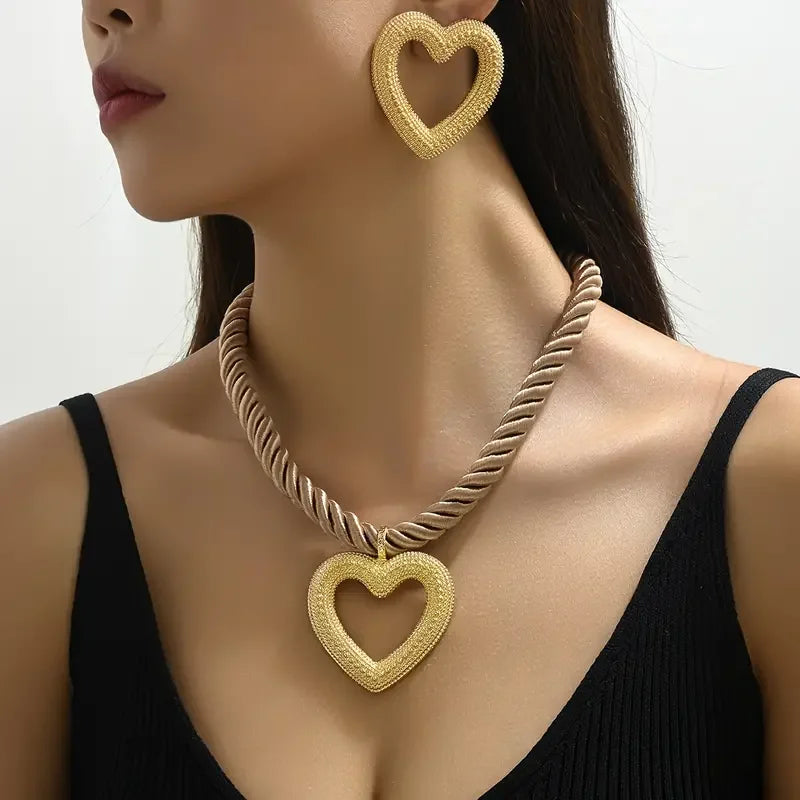 Gold heart-shaped necklace and earrings on a model against a neutral background