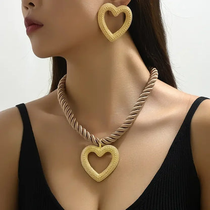 Gold heart-shaped necklace and earrings on a model against a neutral background