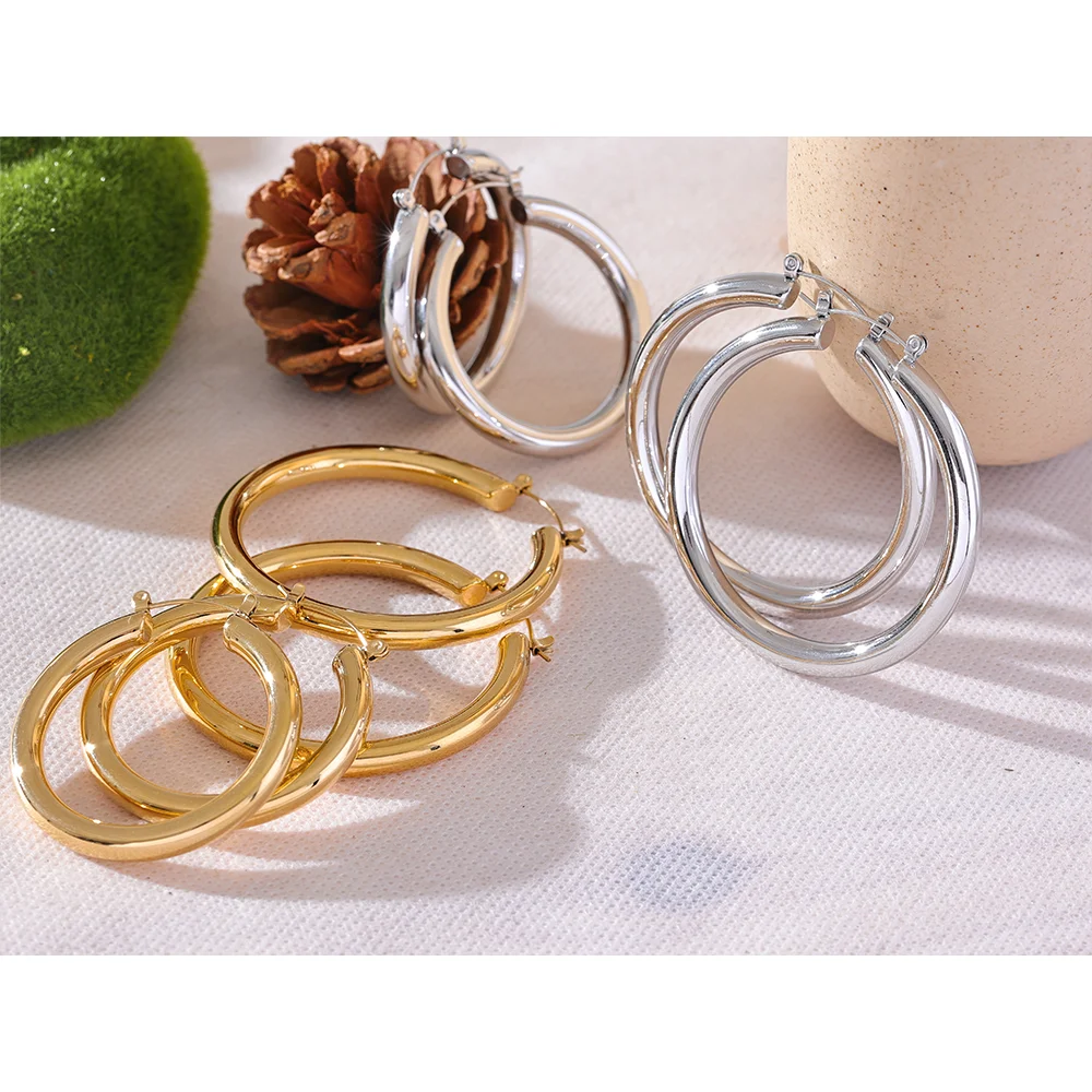 Gold and silver hoop earrings on a textured surface with a natural background.
