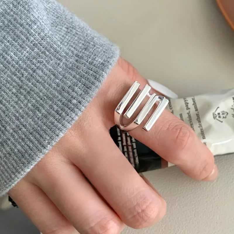 Silver ring on a finger with a neutral background