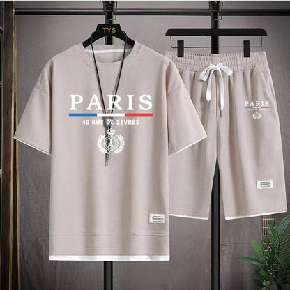 Beige t-shirt and shorts set with 'PARIS' text on hangers against a gray background.