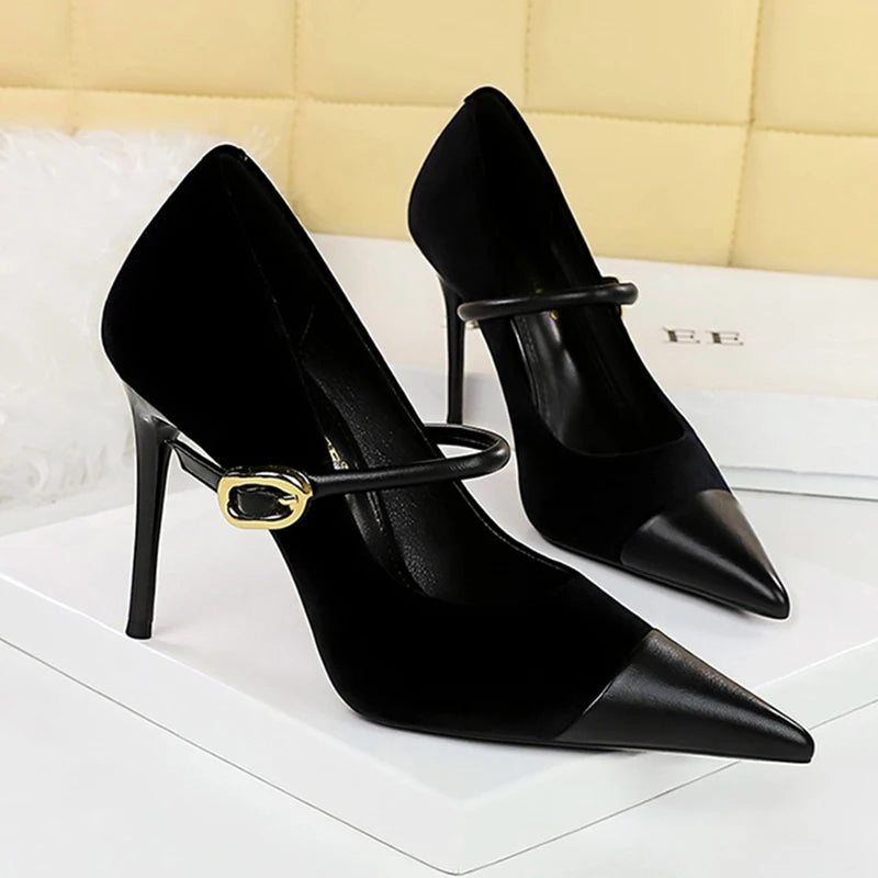 Black high-heeled shoes with gold buckles on a white surface.