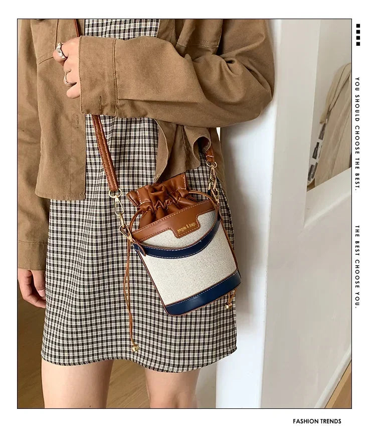 Person wearing a plaid skirt and brown jacket with a two-tone handbag.