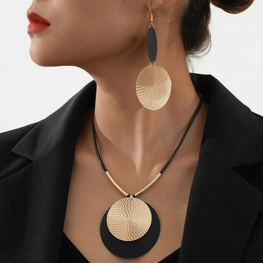 Gold and black circular pendant necklace on a model against a neutral background
