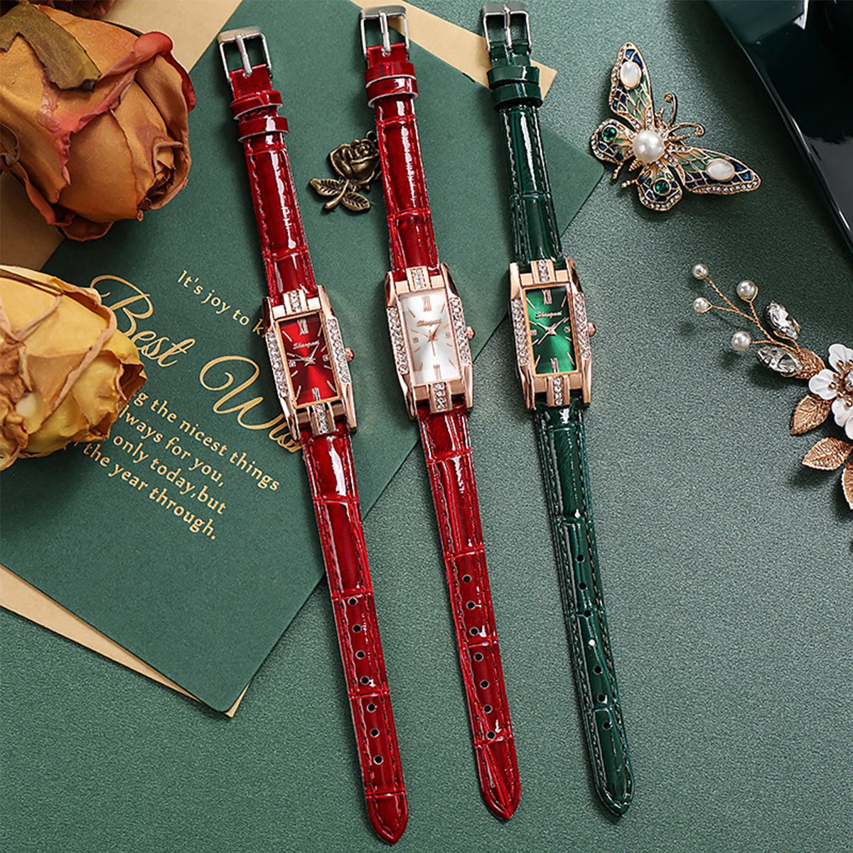 Two watches with red and green straps on a green surface with decorative elements.