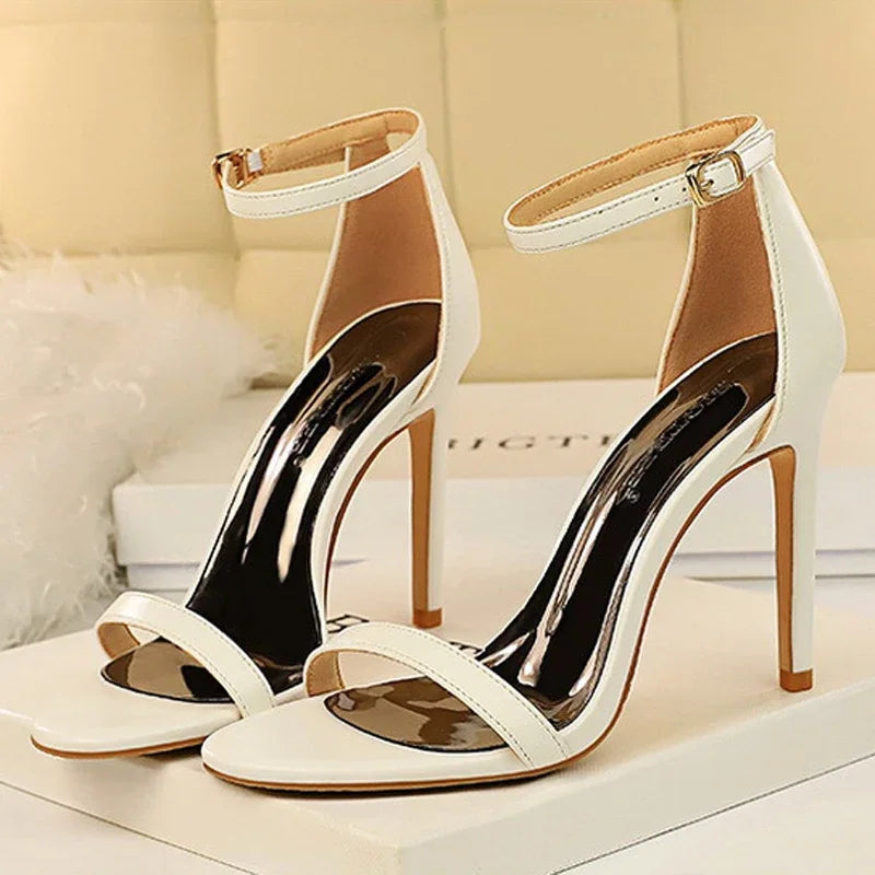 White high-heeled sandals with clear straps on a light background