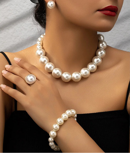 Woman wearing a pearl necklace, earrings, and bracelet with a plain background