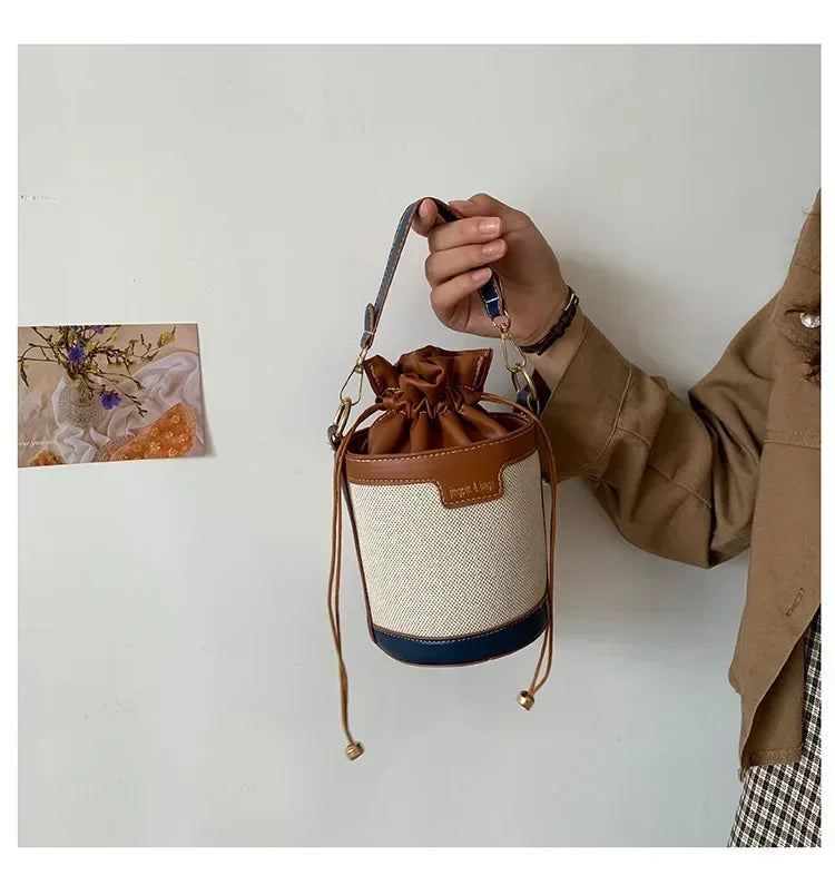 Person holding a drawstring bag with a brown and beige design against a plain background
