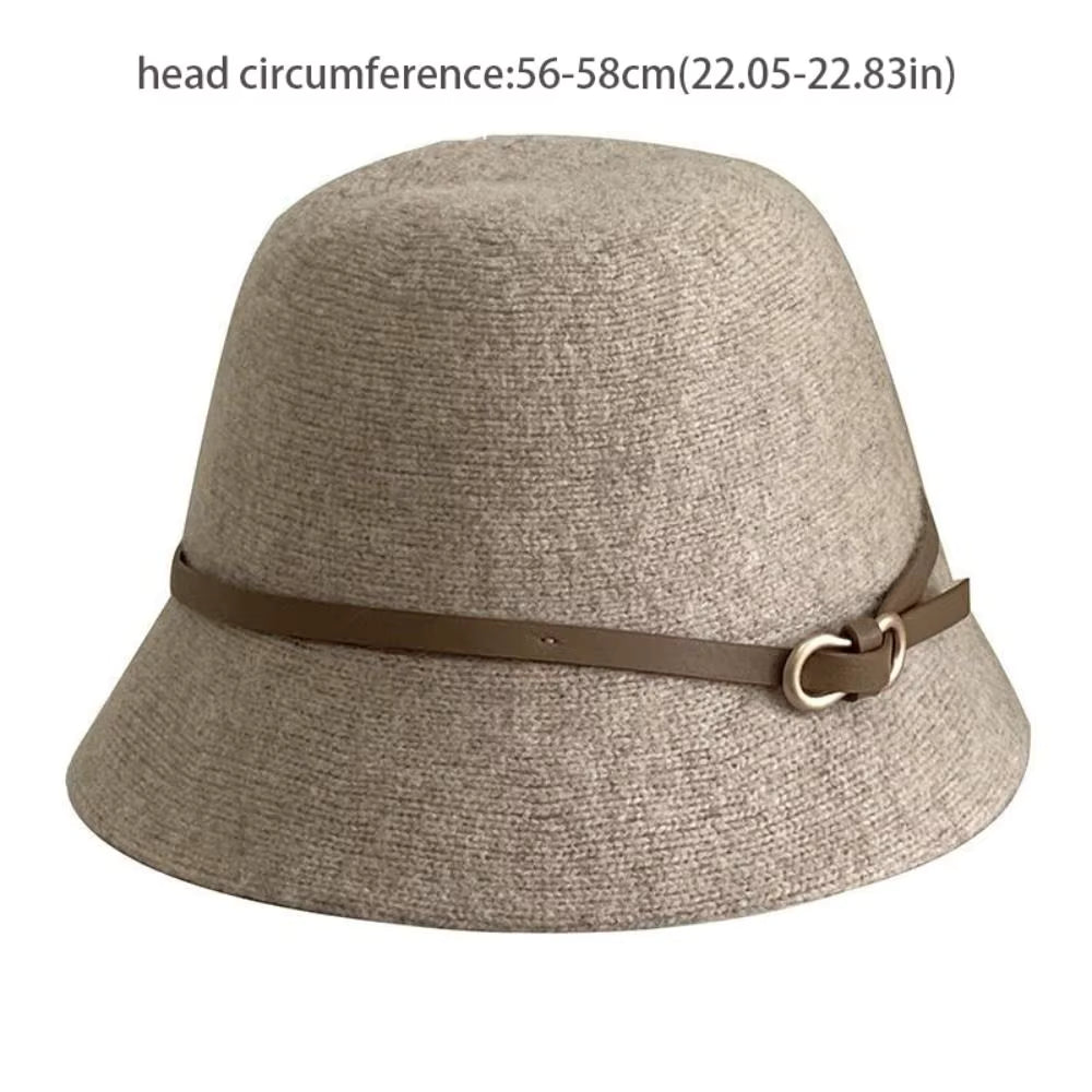 A light beige woven bucket hat with a brown headband and a gold-tone metal ring, shown against a plain white background with text indicating head circumference.