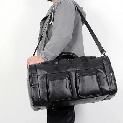 Person holding a black leather duffel bag against a white background