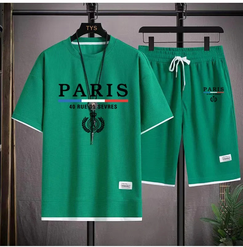 Green 'Paris' t-shirt and shorts set on hangers against a gray background