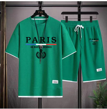 Green 'Paris' t-shirt and shorts set on hangers against a gray background