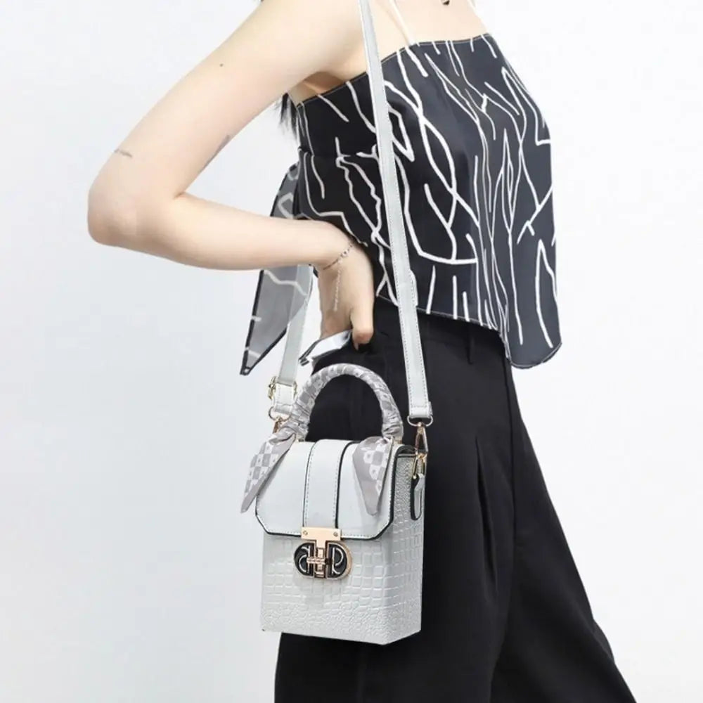 Person holding a gray handbag with a white strap against a light background