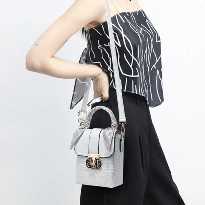 Person holding a gray handbag with a white strap against a light background