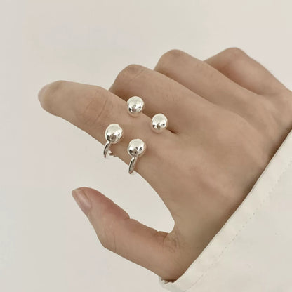 Silver ring with round beads on a hand against a neutral background