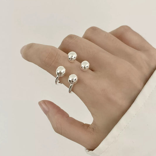Silver ring with round beads on a hand against a neutral background