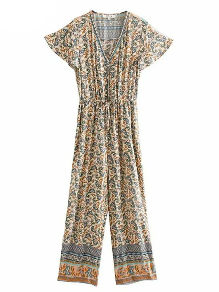 A short-sleeve V-neck jumpsuit with an all-over bohemian floral print in beige, orange, and blue, featuring a drawstring waist and patterned hems.