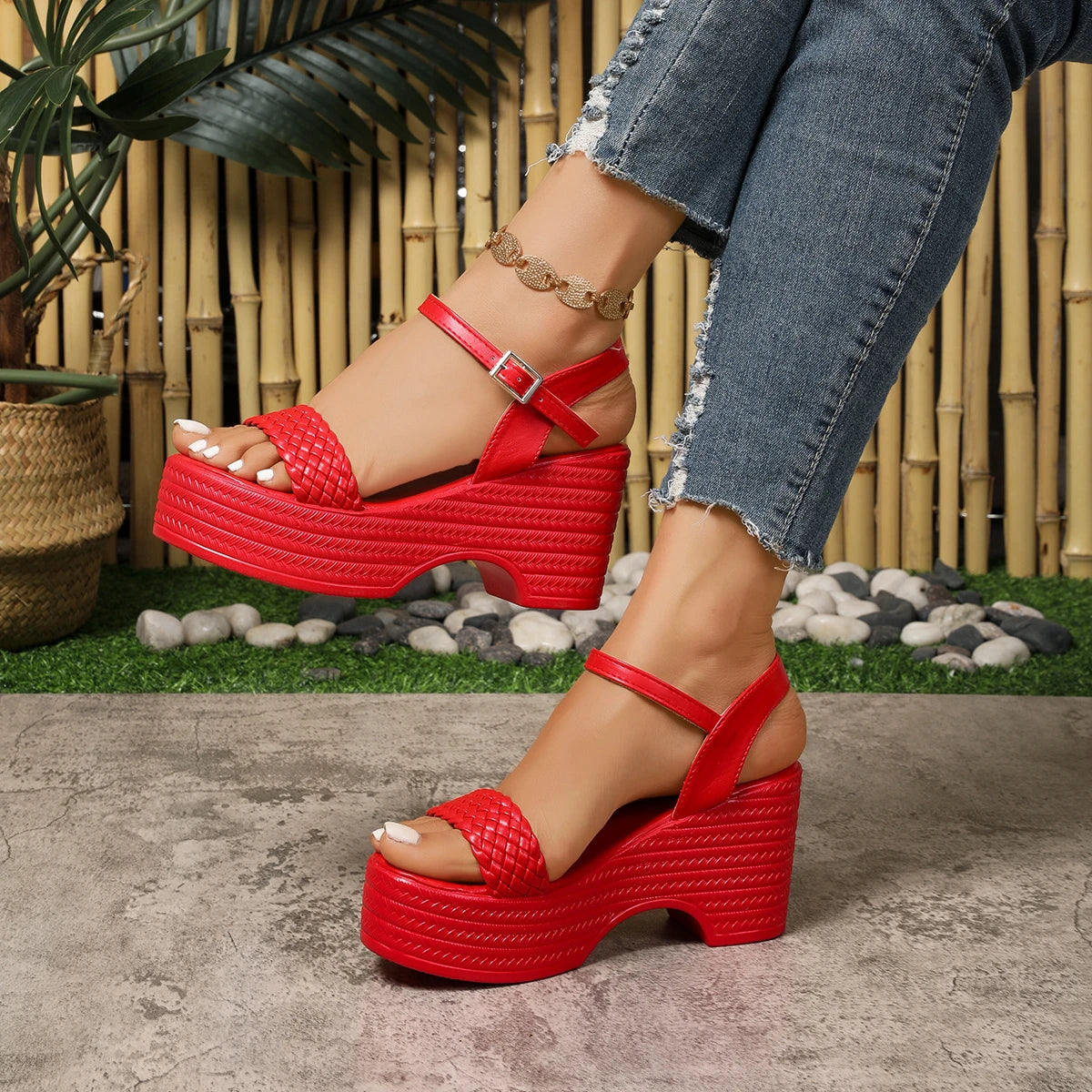 Red platform sandals worn with denim jeans against a natural background