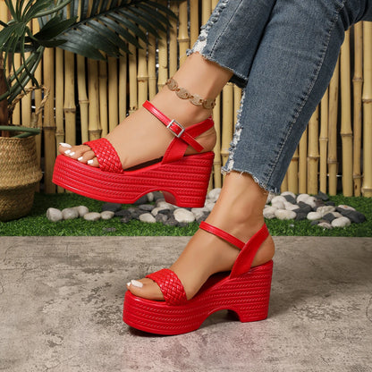 Red platform sandals worn with denim jeans against a natural background