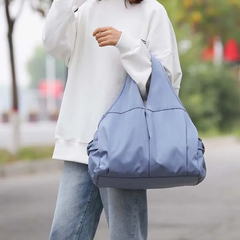 Person holding a blue bag outdoors with a blurred background