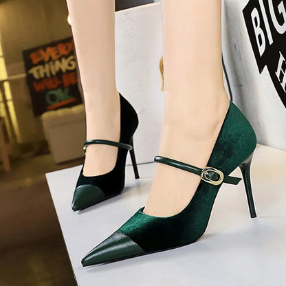 Green high-heeled shoes with a strap worn by a person, with a blurred indoor background.