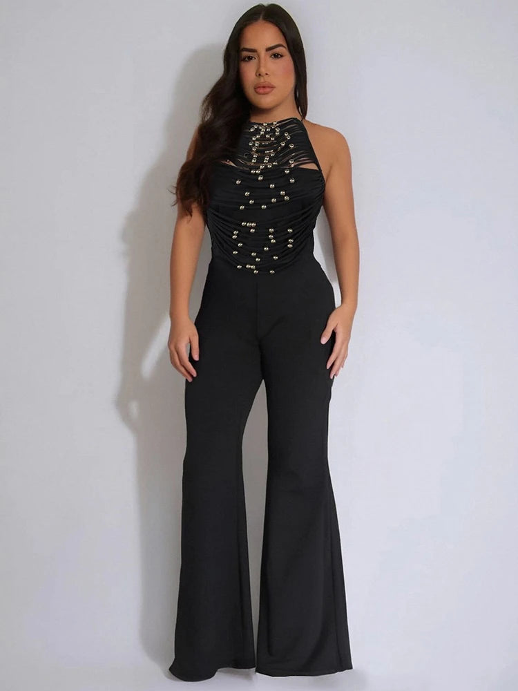 Woman wearing a black embellished jumpsuit against a white background