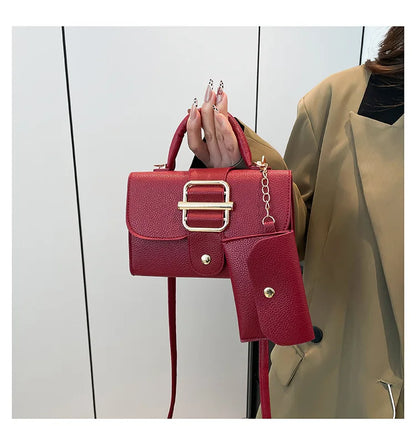 Red handbag with gold accents held by a person wearing a beige coat against a white background