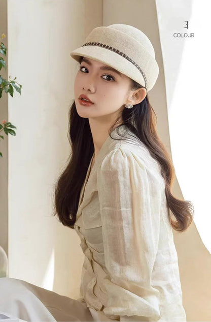 Woman wearing a white cap and light-colored shirt indoors