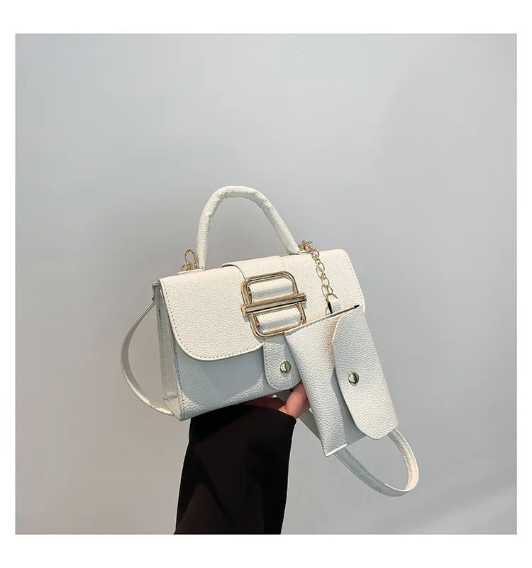White handbag with gold accents held against a gray background