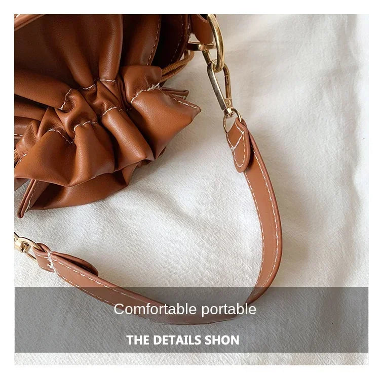 Brown leather handbag with ruffled details on a white background
