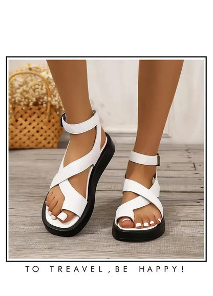 White sandals worn by a person on a wooden floor with a woven basket in the background.