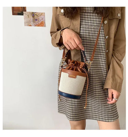 Person holding a drawstring bag with a plaid skirt and beige jacket against a white background