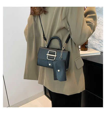 Person wearing a beige coat with a navy handbag featuring a gold chain strap.