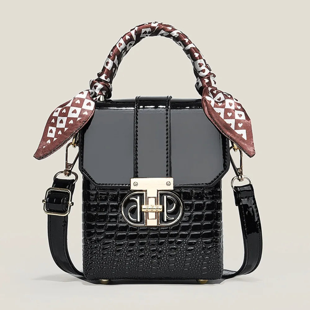 Black textured handbag with patterned handle on a light beige background