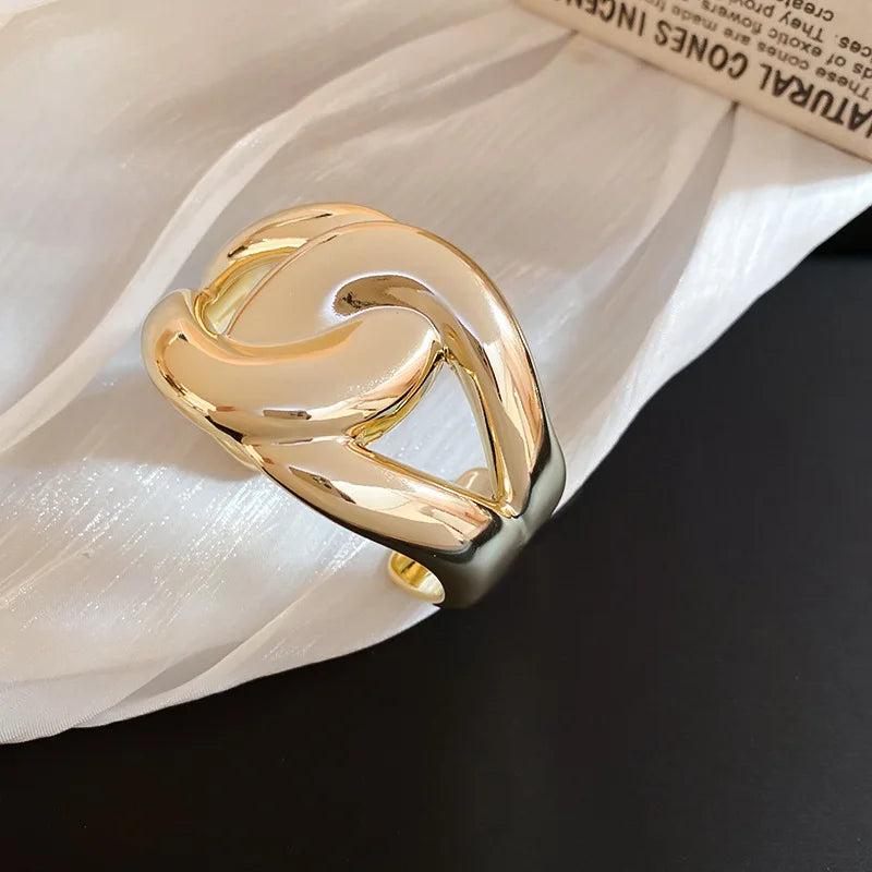 Gold ring with a wavy design on a white shell background