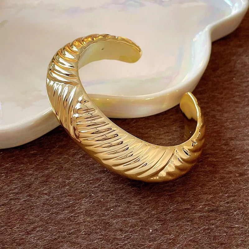 Gold hoop earring on a textured surface