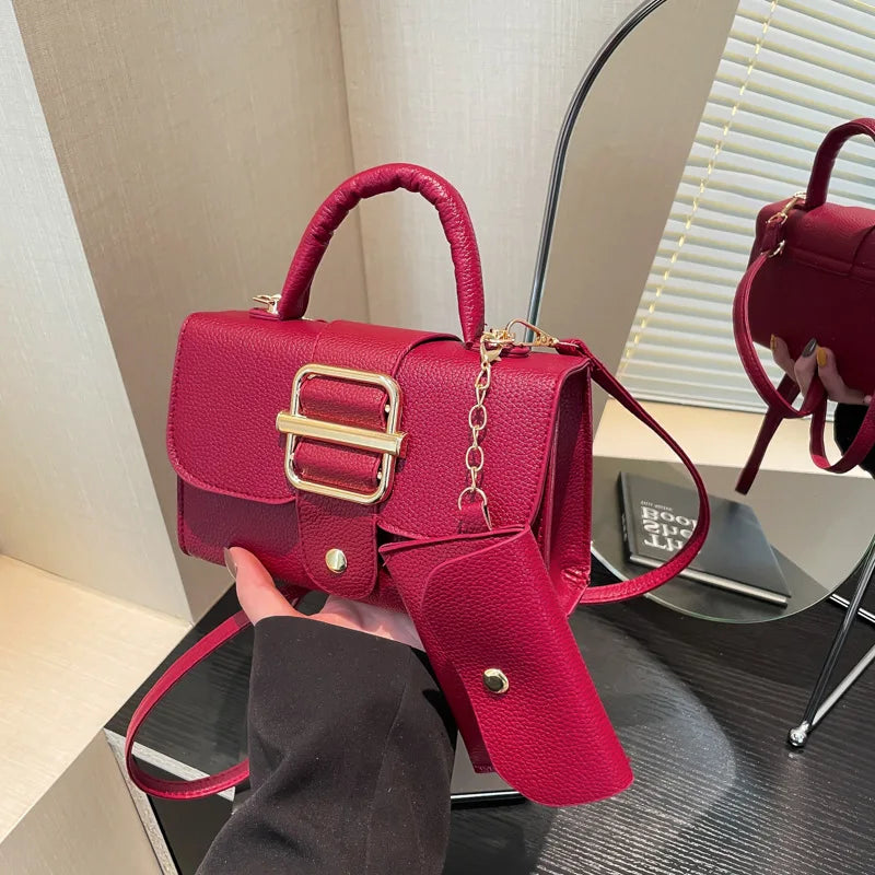 Red handbag with gold accents held by a person, placed on a surface.