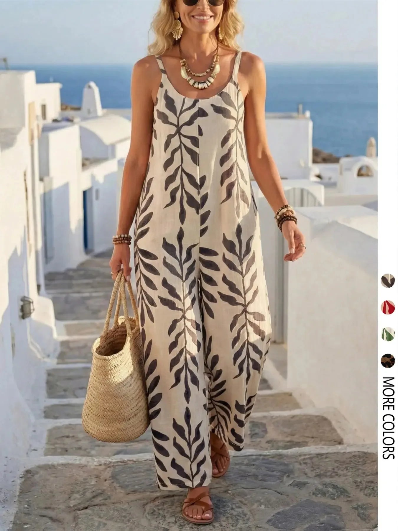 Woman in a leaf-patterned dress standing on a Mediterranean-style street with ocean view.