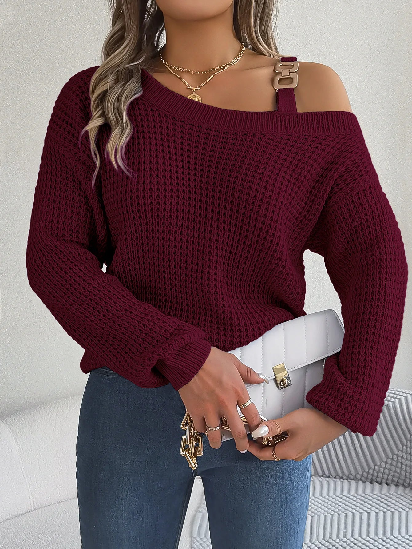 Person wearing a burgundy off-shoulder sweater with a white background