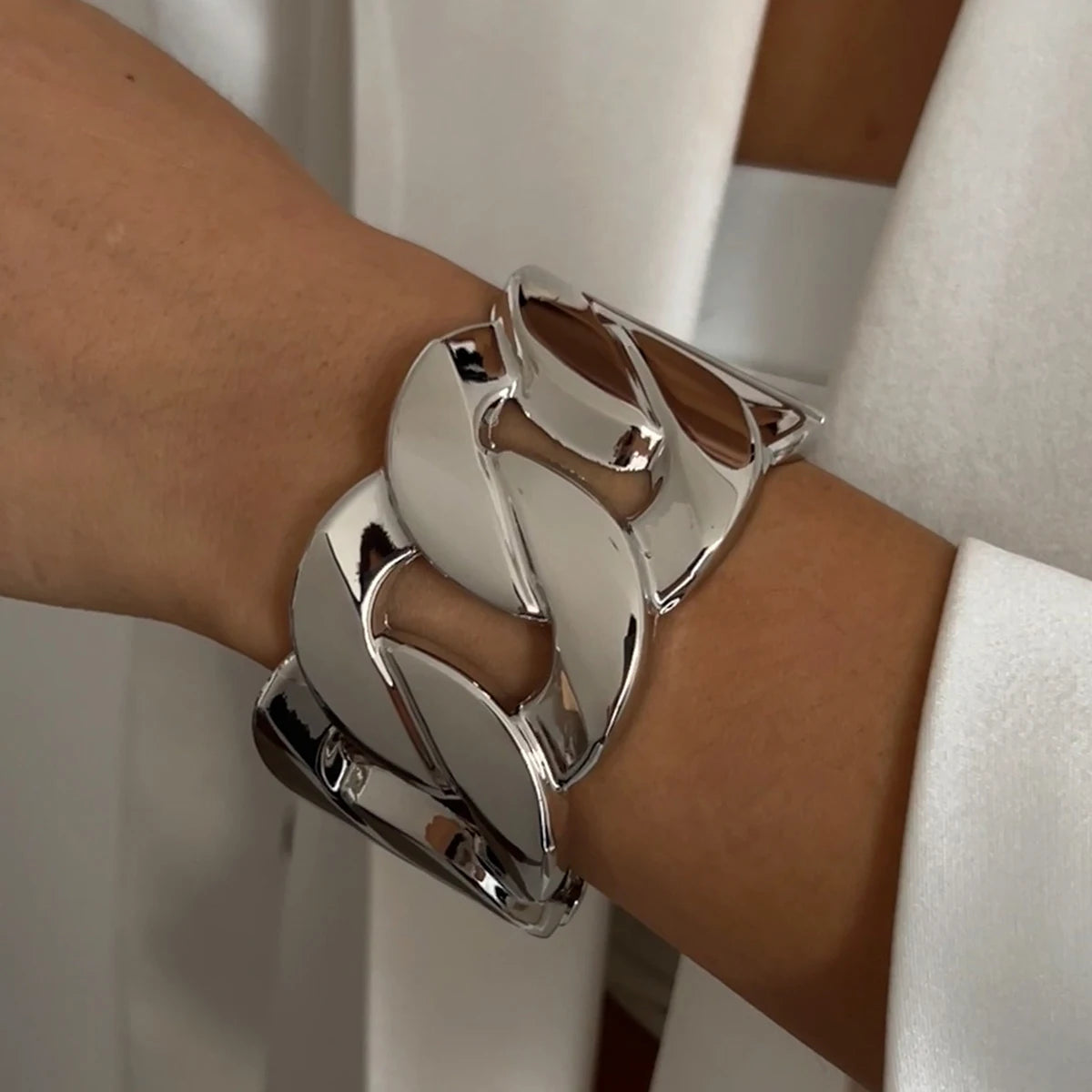 Silver bracelet on a wrist with a neutral background