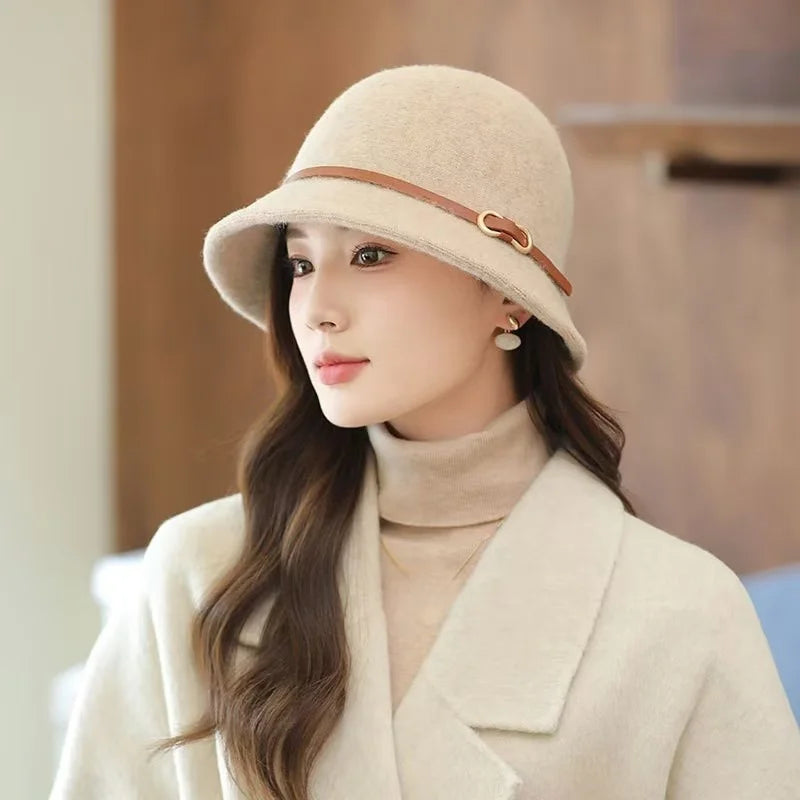 Woman wearing a beige hat and coat in an indoor setting