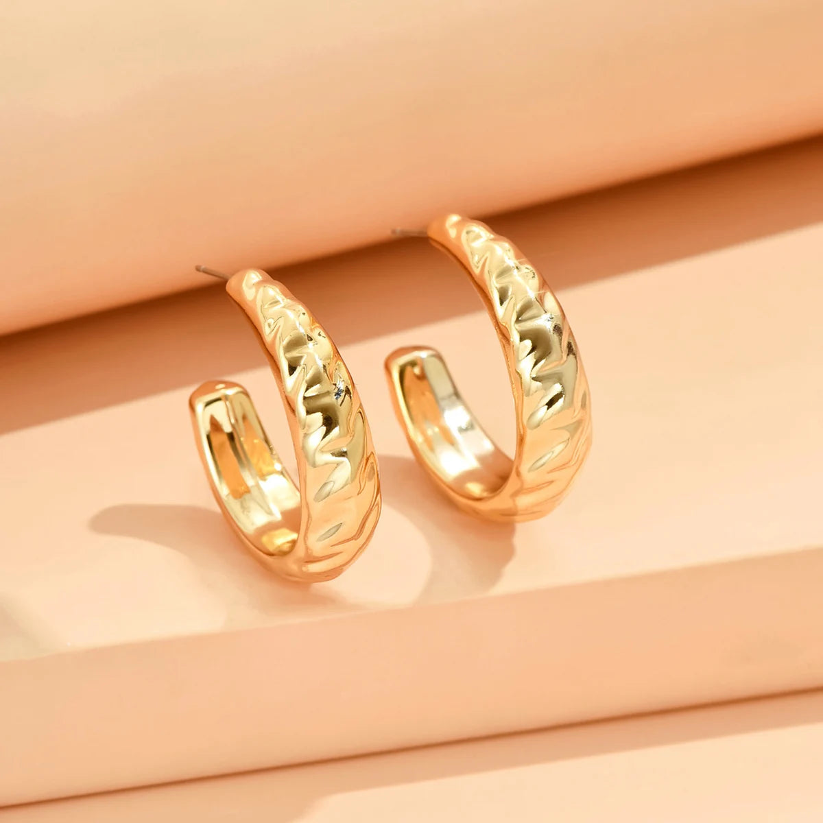 Gold hoop earrings on a peach-colored background