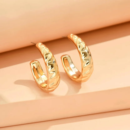 Gold hoop earrings on a peach-colored background
