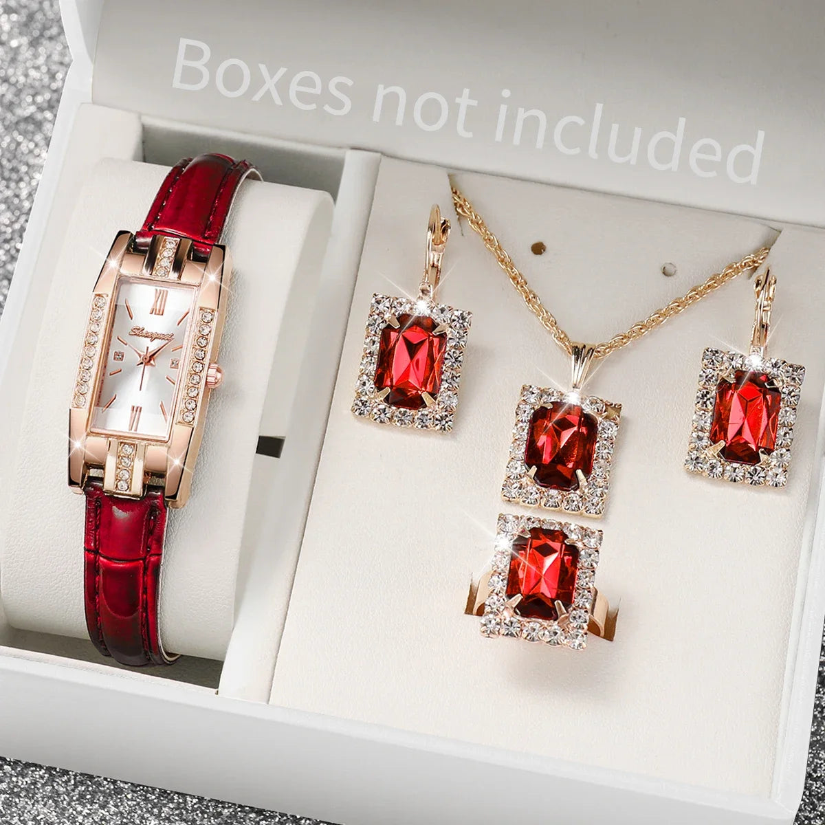 Jewelry set with red gemstones including a watch, necklace, and earrings on a white background.