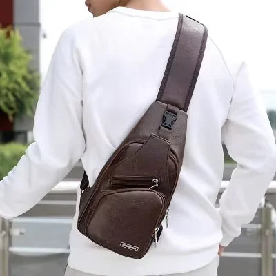 Person wearing a brown leather sling bag over one shoulder outdoors.