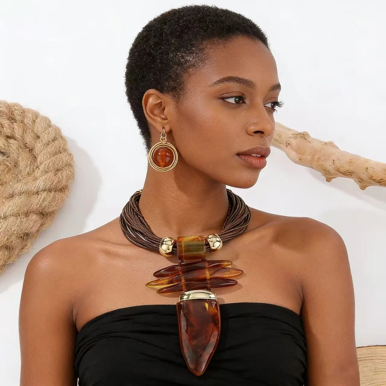 Woman wearing a large, brown necklace with gold accents against a neutral background