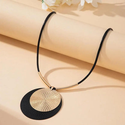 Necklace with black and gold pendant on a beige background