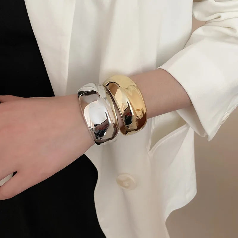Gold and silver bangles on a person's wrist with a blurred background