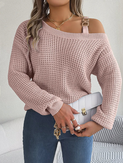 Person wearing a pink off-shoulder sweater holding a white handbag against a neutral background