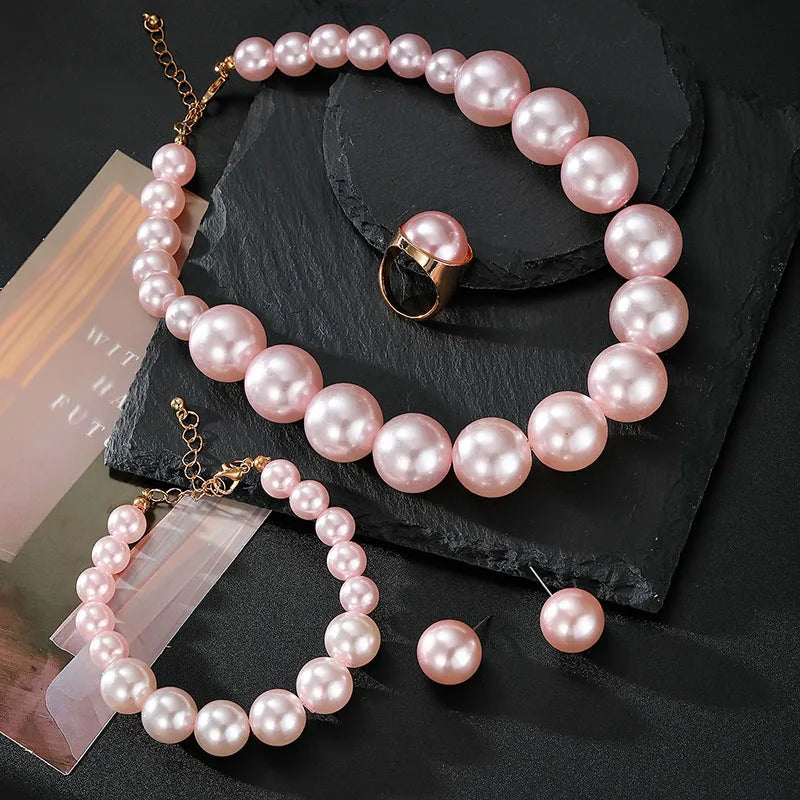 Pearl necklace and bracelet set on a dark surface with a magazine underneath.